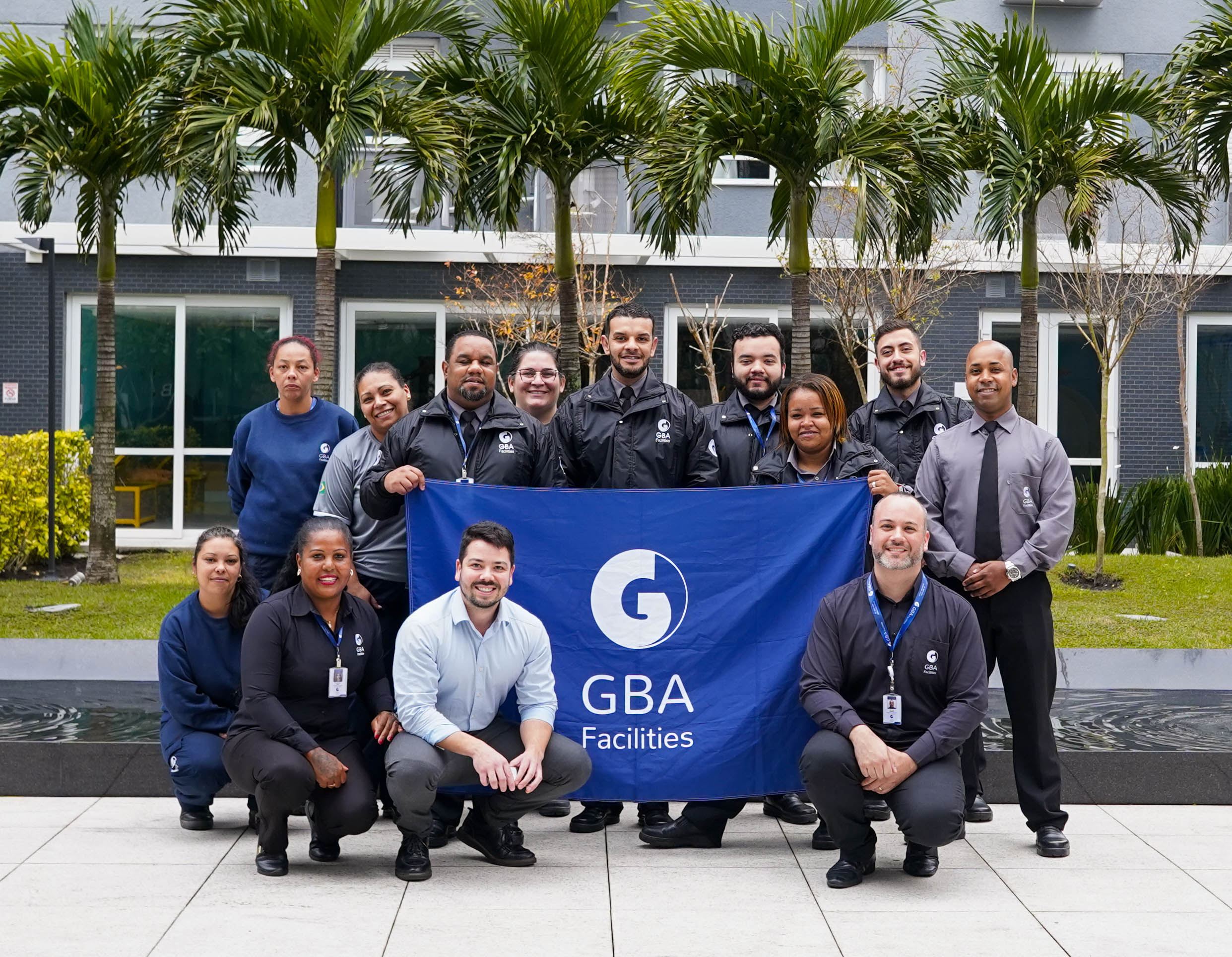 Equipe GBA Facilities reunida em torno da bandeira da empresa