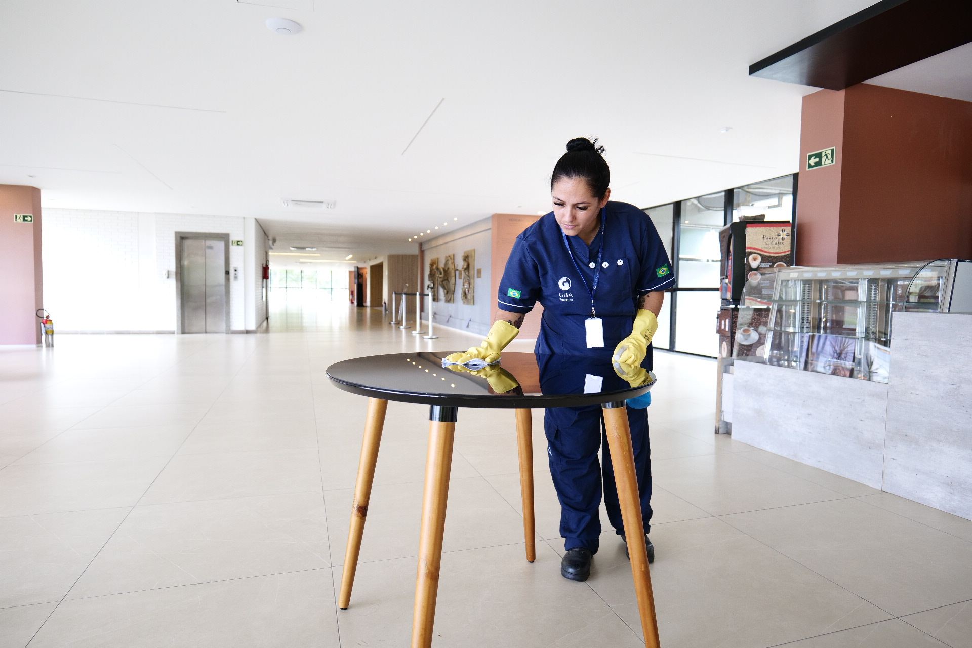 Profissional da GBA higienizando mesa em saguão corporativo